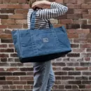 To the Wild Waxed Canvas Bag in blue - against a brick wall